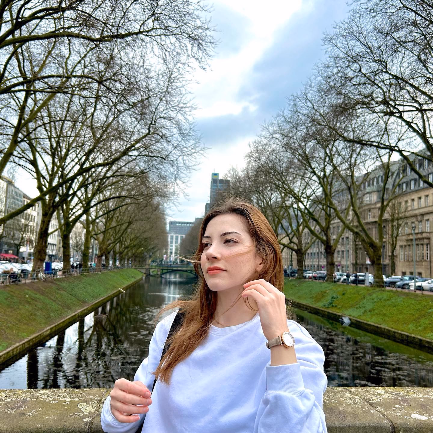 Patient by a tree-lined canal after rhinoplasty in Ankara, three-quarter view